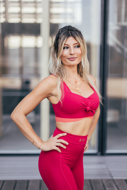 La coach sportive Julie Pujols se trouve debout avec les mains sur les hanches.Elle porte la tenue azar gang couleur framboise.