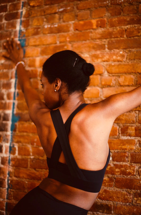 femme de dos portant une brassière noire croisée de la marque AZAR