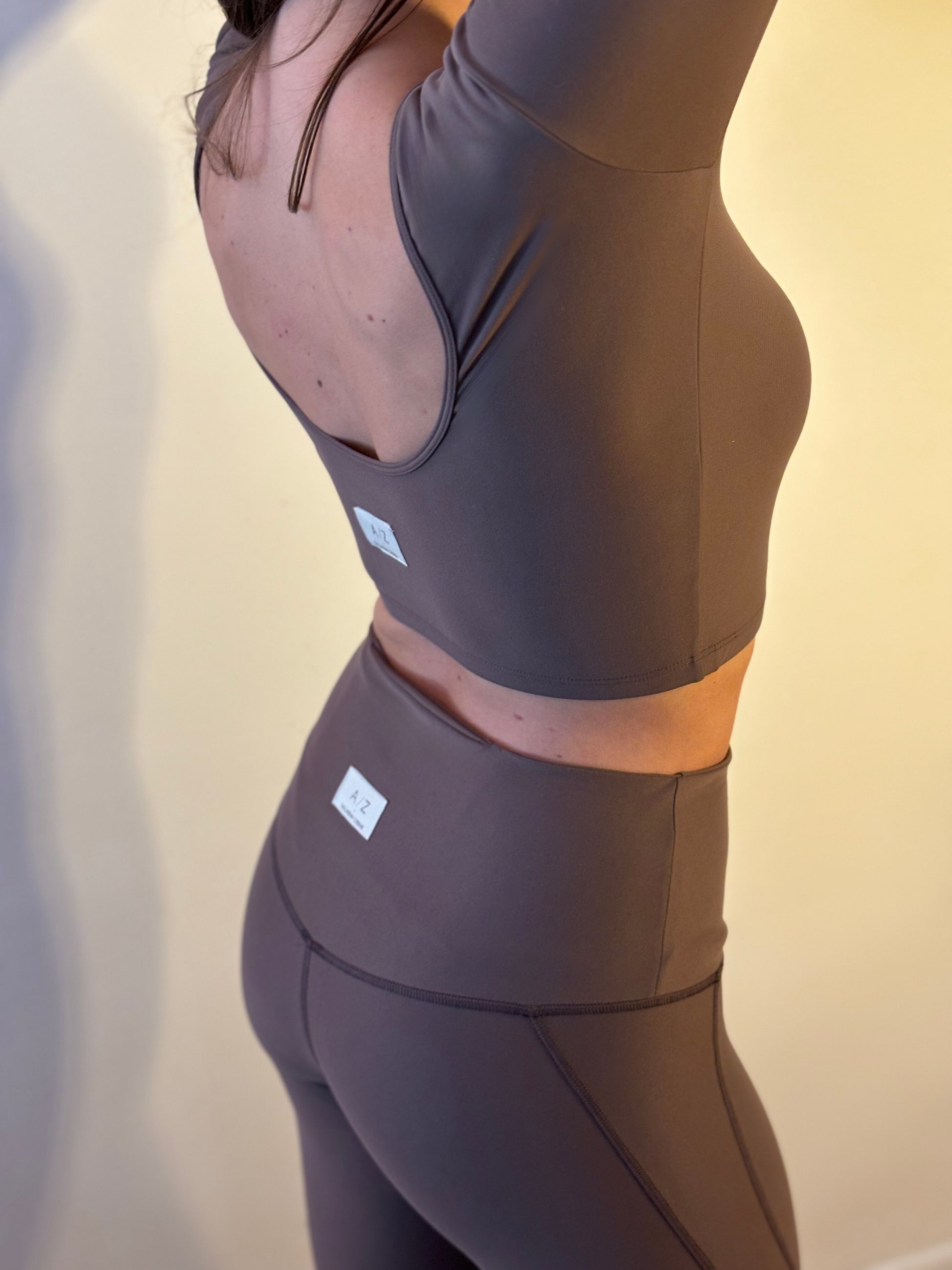 femme debout de dos portant un top de sport couleur marron