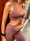 femme contre le mur portant un ensemble de sport brassière et legging de couleur terracotta, de la marque AZAR GANG