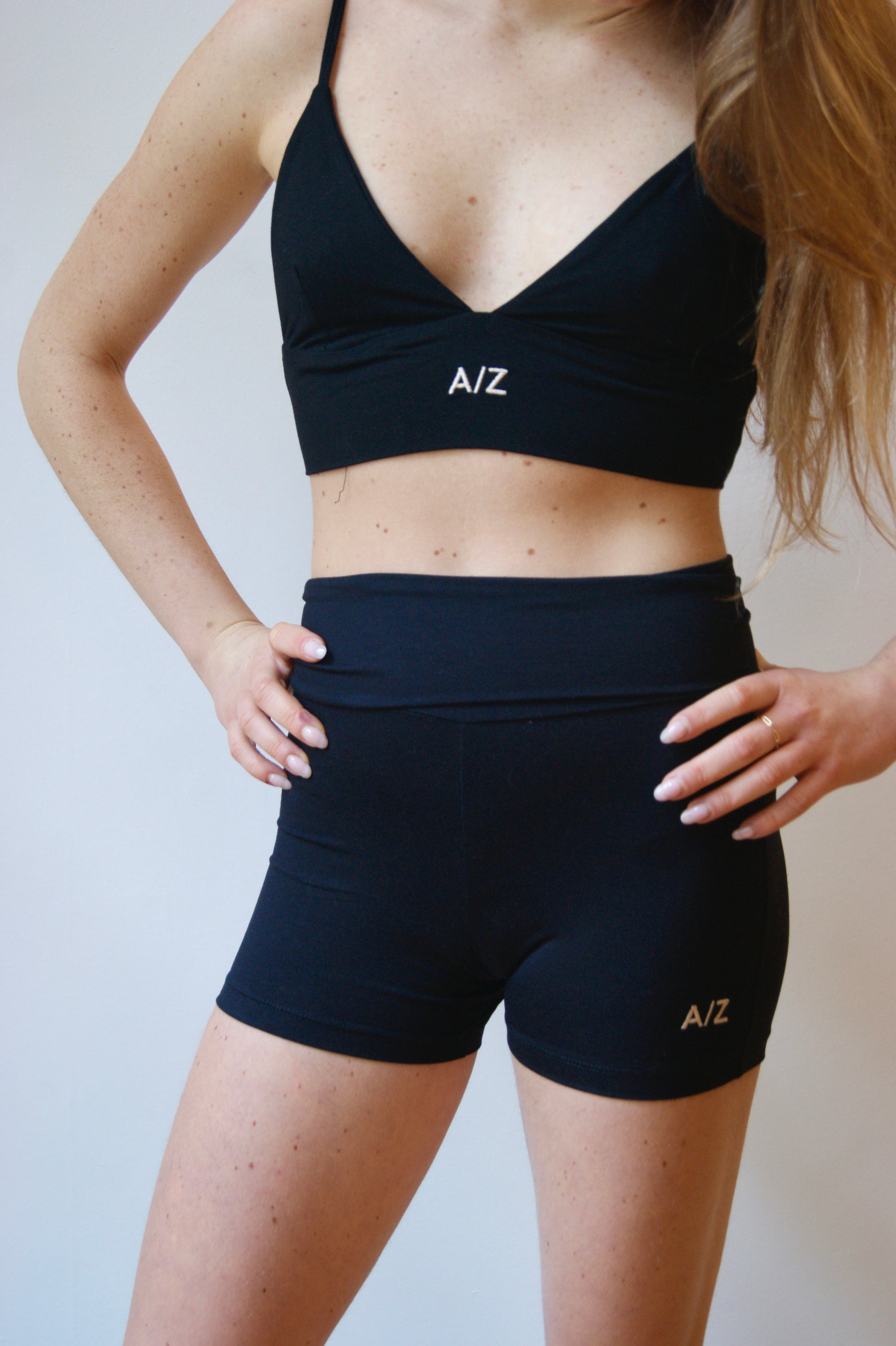 femme debout avec les mains sur les hanches, portant la brassière et le short noir de la collection CALM de AZAR GANG